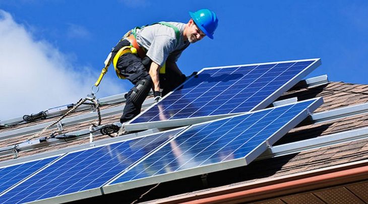 Foto de um homem instalando uma placa de captao de energia solar