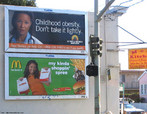 Foto de dois outdoors, um com um apelo ao controle da alimentao infantil (e contra a obesidade infantil), e o outro com uma propaganda de uma rede de fast-food. Palavras-chave: Outdoor. Controle. Alimentao. Obesidade infantil. Criana. Propaganda. Fast-food. Sade.