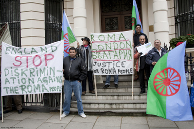 A bandeira do povo Rom (os ciganos) foi criada no Congresso Mundial Rom em 1971 e trs em si smbolos importantes para a identidade cigana. Nesta foto, ciganos blgaros protestam contra a discriminao sofrida na Inglaterra (Mais informaes: http://www.vice.com/read/the-gypsy-suicide-and-drug-abuse-rates-have-exploded) - discriminao essa que  o grande trao de unio entre os ciganos do mundo inteiro. O povo cigano, que tambm compe a sociedade brasileira, representa a diversidade cultural cigana do planeta. Felizmente, h muitos ciganos na escola, mas muitas vezes a criana cigana  vtima do preconceito e do desconhecimento, e por isso esconde seu pertencimento. Para que as situaes de perseguio e privaes cessem,  preciso valorizarmos o dilogo e o respeito, para aprendermos uns com os outros e neutralizarmos informaes equivocadas e lendas sem fundamento que se perpetuam de gerao a gerao. Quer saber mais sobre essas questes? Contacte o Departamento de Diversidade - DEDI : (41) 3340-1688 (41) 8409-1677. Palavras-chave: Cartaz. Palavras de ordem. Justia. Direito. Sociedade.  Gitanos. Itinerncia. Diversidade. Ortografia.