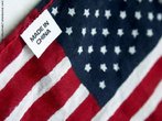Foto de uma bandeira dos Estados Unidos com tarja indicativa de que foi fabricada na China.  Palavras-chave: fabricao, contradio, tecido, smbolo, pases.