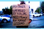 Foto de um homem que leva um cartaz com o dizer: "Meu pai foi morto por ninjas. [Preciso de] dinheiro para ter aulas de karat".   Palavras-chave: Pedido. Esmola. Ajuda. Explicao. Histria.