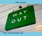 Foto de uma placa verde indicando a sada ('Way out").  Palavras-chave: Placa. Natureza. Sada. Limite. Sobrevivncia. Humanidade.
