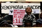 Foto de uma manifestao pblica contra a xenofobia (averso a estrangeiros). No meio, um menino e um cartaz com os dizeres: "No encoste em meu irmo. No encoste em minha irm. ABAIXO a xenofobia".  Palavras-chave: Reivindicao. Criana. Povo. Injustia.