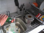  Foto de uma pessoa lavando pratos - ação comum no ambiente culinário, uma vez que, pratos, talheres e louças necessitam ser lavados constantemente.  Palavras-chave: lavar, campo semântico, pratos, cozinha.