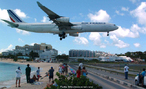 Foto de um avio aterrissando em uma pista prxima a uma praia. Vrias pessoas observam o grande veculo aproximando-se.  Palavras-chave: transporte areo, aeronave, turismo, cu.