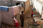Foto de um bairro pobre em uma cidade da Argélia. Veem-se crianças transitando e um morador de costas.  Palavras-chave: pobreza, Argélia, África, criança, favela.