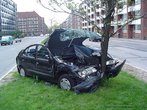 Foto de um carro colidido contra uma árvore, em via pública.  Palavras-chave: acidente, carro, álcool, narrativa, interdiscurso, cinto de segurança, imprudência.