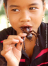 : Foto de uma moa comendo uma tarntula. O consumo de insetos no  to comum no Brasil, mas faz parte do cardpio de diversos outros pases, entre eles Mxico e Camboja.  Palavras-chave: insetos, interculturalidade, cultura, cardpio, Camboja, alimentao. 