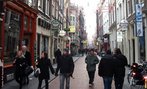 Foto de uma rua da regio antiga de Amsterd, Holanda. Veem-se transeuntes circulando e muitas lojas.  Palavras-chave: interculturalidade, cidade, comrcio, urbano. 