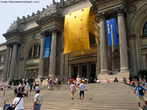 Foto da fachada do Museu Metropolitano de Arte, em Nova Iorque. Veem-se várias pessoas subindo e descendo as escadarias, e algumas sentadas nos degraus.  Palavras-chave: atração, turismo, arte, exposição.