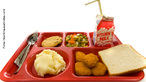 Foto de uma bandeja de almoço (lunch tray), comum em escolas dos Estados Unidos. Sobre o utensílio, observam-se talheres, um biscoito, legumes, leite, purê, empanados e pão.  Palavras-chave: dieta, alimentação, cantina, colégio. 
