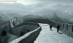 Descrição: Foto em preto e branco da Grande Muralha da China, mostrando duas pessoas descendo a estrada que existe sobre a construção.  Palavras-chave: China, muralha, maravilhas, antiguidade, oriente, descrição.