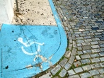 Foto de um trecho de calçada ou asfalto com o símbolo dos cadeirantes. Palavras-chave: calçada, asfalto, cadeirante, deficiência, mobilização, lei, direito, acesso.