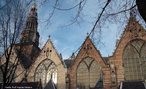 Foto da área externa da "De Oude Kerk" (The Old Church), em Amsterdã, construída a partir do século XIII. Veem-se as estruturas da fachada em estilo tipicamente holandês, e um campanário.  Palavras-chave: Holanda, Amsterdã, igreja, religião, Idade Média, vitrais. 