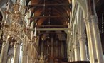 Foto de uma igreja no centro de Amsterdã, com o interior da nave em estilo gótico. Veem-se candelabros e colunas e, ao fundo, um órgão de tubos. Palavras-chave: The Old Church, Holanda, igreja, idade média, Europa.