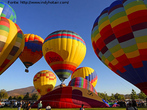 Foto de vários balões dirigíveis sendo lançados, cercados de pessoas, sobre um terreno plano.  Palavras-chave: balão, meios de transporte, evolução.