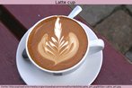 Foto de uma xícara de latte (lá - te), isto é, café com leite. Na superfície do líquido, observa-se um desenho. Trata-se de uma arte, explorada por cafeterias especializadas. Palavras-chave: Bebida. Galicismo. Alimentação. Folha.