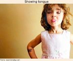 Foto de uma menina de vestido, mostrando a língua. Palavras-chave: Atitude. Mensagem. Sentido. Significado. Interpretação. Interculturalidade. Inferência.