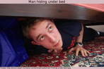 Nesta foto, um rapaz esconde-se de algo sob a cama, e olha para ver se está sendo visto. Palavras-chave: Ação. Narrativa. História. Perseguição. Verbo. To hide.