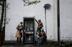 Grafite do artista britânico Bansky, feito em Cheltenham, Gloucestershire, na Inglaterra. Na imagem, três homens de casaco, óculos escuros e escutas telefônicas aparecem em volta de uma cabine de orelhão público.<br> Palavras-chave: Grafite. Crítica. Segurança. Informação. GCHQ. Espionagem.