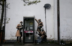 Grafite do artista britnico Bansky, feito em Cheltenham, Gloucestershire, na Inglaterra. Na imagem, trs homens de casaco, culos escuros e escutas telefnicas aparecem em volta de uma cabine de orelho pblico.<br> Palavras-chave: Grafite. Crtica. Segurana. Informao. GCHQ. Espionagem.