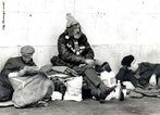 Foto de trs homens sentados na calada, aparentemente sem ter aonde ir. V-se tambm uma garrafa e um rdio no cho.  Palavras-chave: descrio, moradores de rua, sem teto.